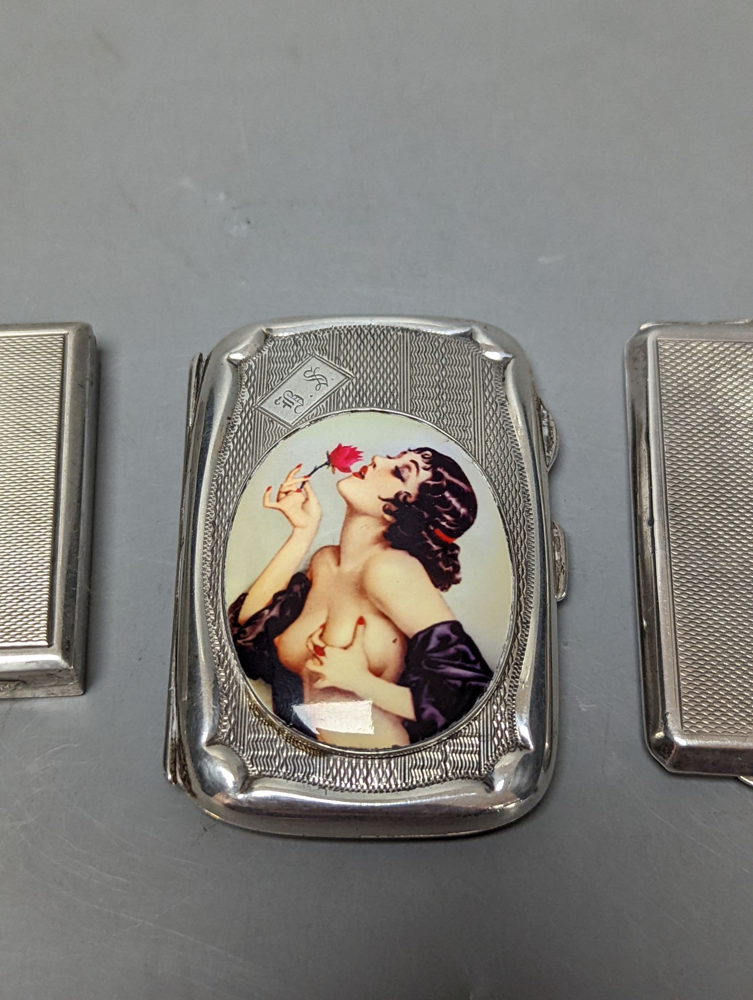 A silver cigarette case, an Austro Hungarian white metal box and a silver cigarette case with panel decorated with a topless lady, 77mm, gross weight 172 grams.